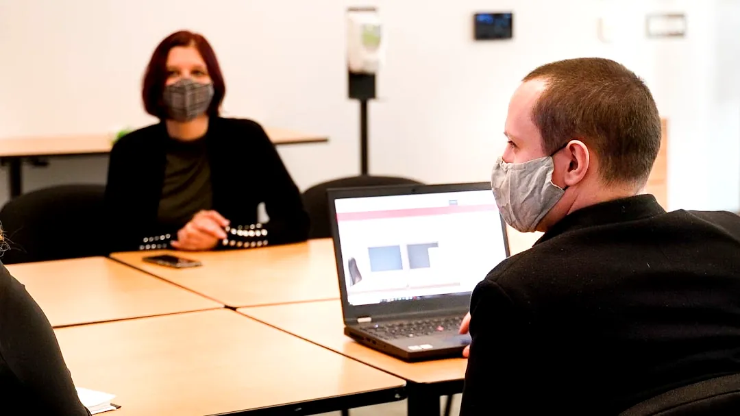 a group of people sitting around a table wearing face masks