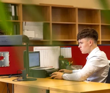 a man sitting at a desk in front of a computer monitor
