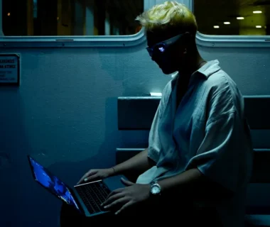 A man sitting on a train using a laptop computer