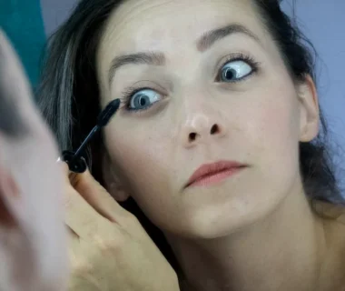 a woman is putting mascara on her face
