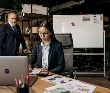 Business professionals collaborating in a modern office setting with laptop and documents.