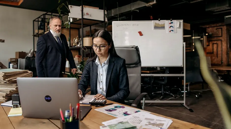 Business professionals collaborating in a modern office setting with laptop and documents.