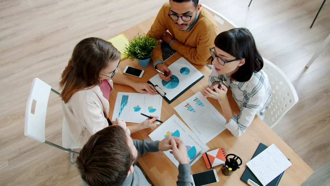 Four people collaborating around a table with documents.