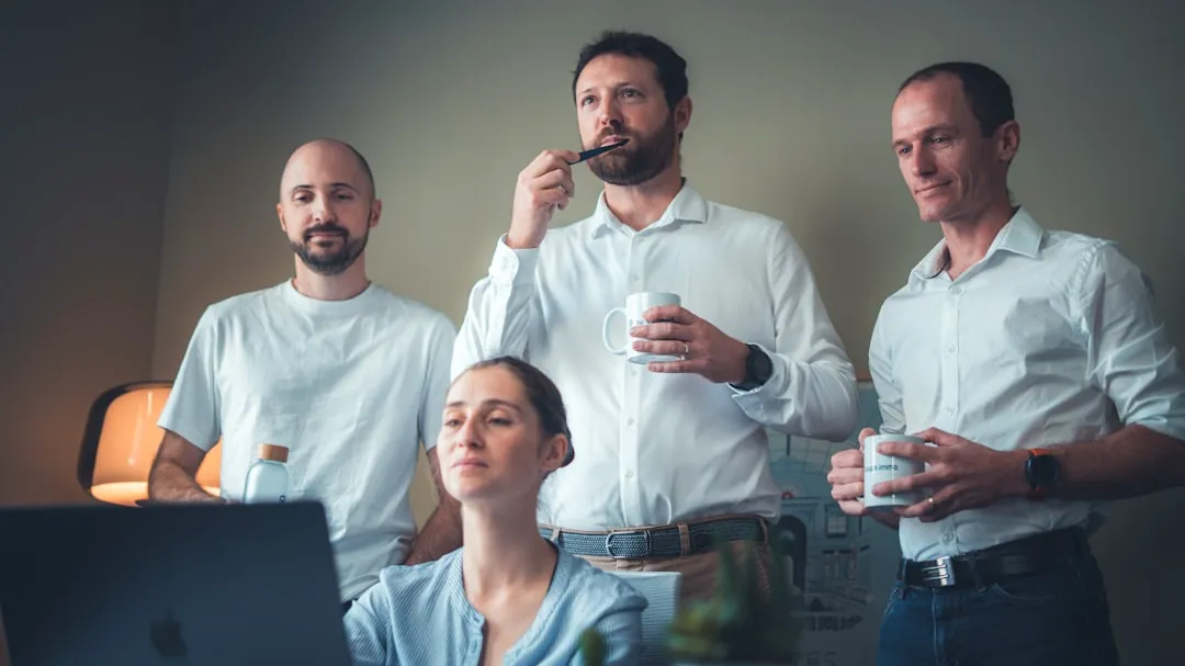 Four people in a room looking at a laptop.
