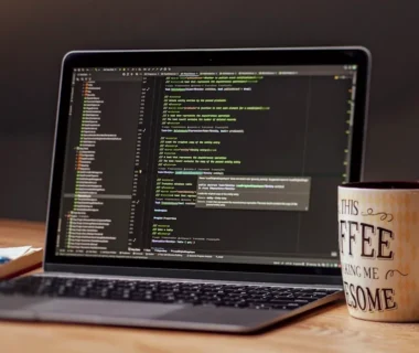 Laptop displaying code with a coffee mug nearby.