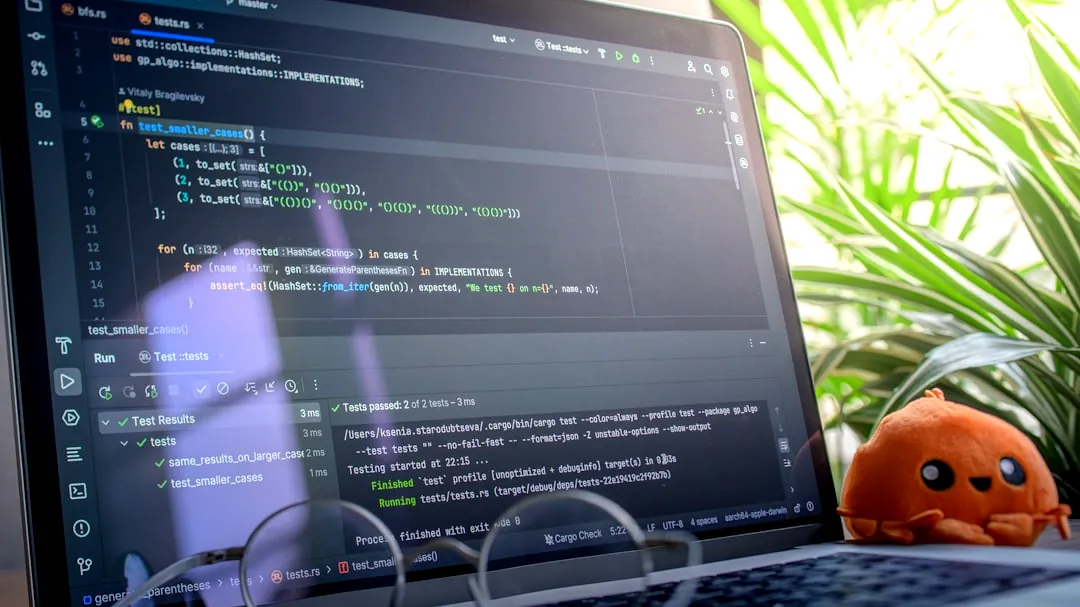 Laptop screen displaying code with glasses and plush toy.