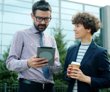 Man and woman discussing tablet outside office building
