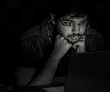 man in black and white striped shirt using black laptop computer