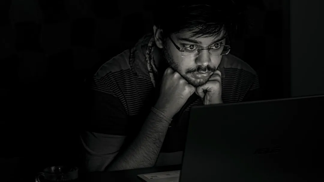man in black and white striped shirt using black laptop computer