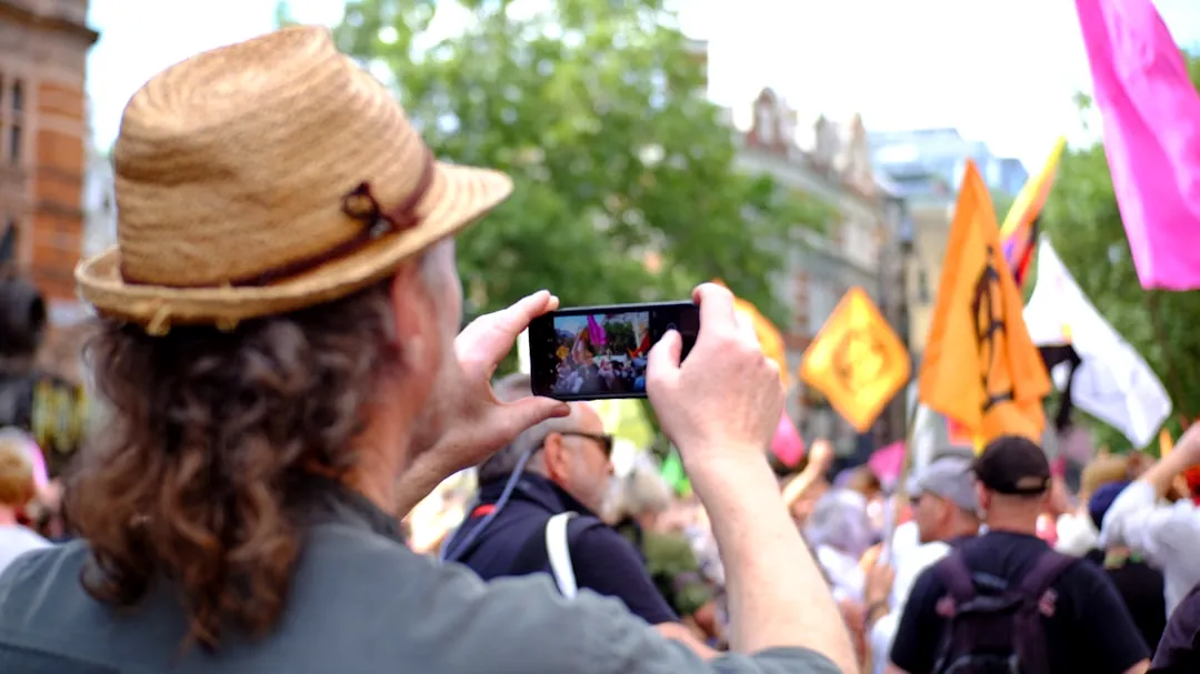 man in brown hat holding black smartphone