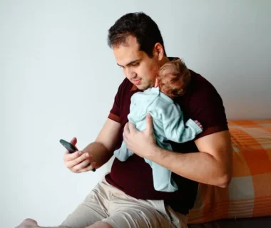 man in green shirt carrying baby