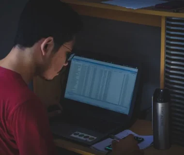 man in red shirt using black laptop computer