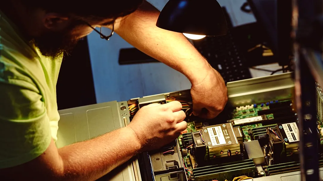 Man repairing a computer server under a lamp.