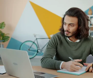 Man working at a desk with a laptop and notebook.