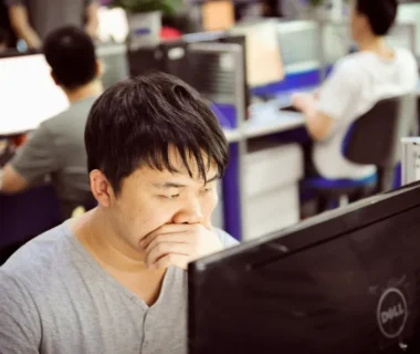 Man yawning while working at computer in office