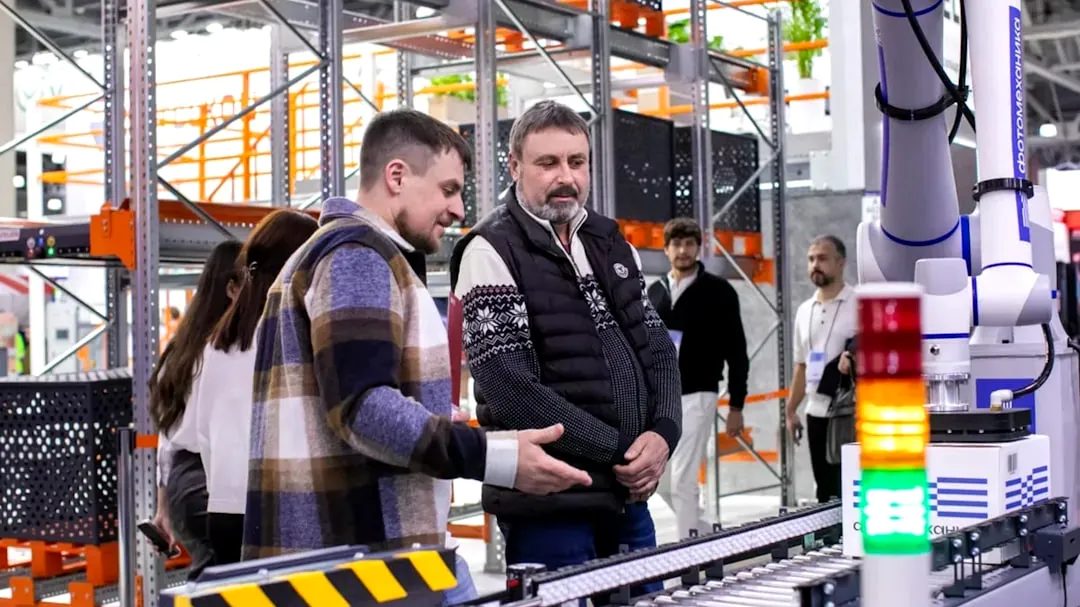 Men observe automated conveyor belt system in warehouse