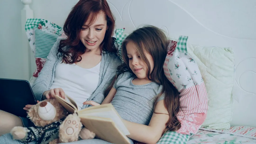 Mom and daughter read a book together.