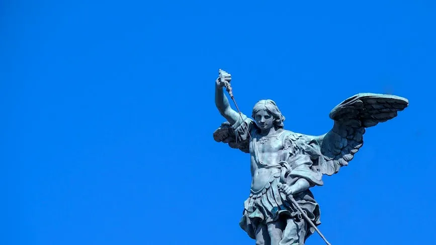 Stunning view of Archangel Michael statue in Rome with a bright blue sky backdrop.