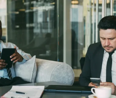 Two businessmen using devices in a modern office.
