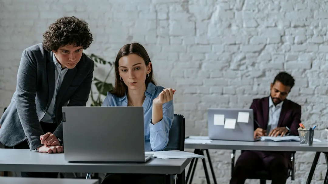 Two colleagues collaborating on a laptop in office.