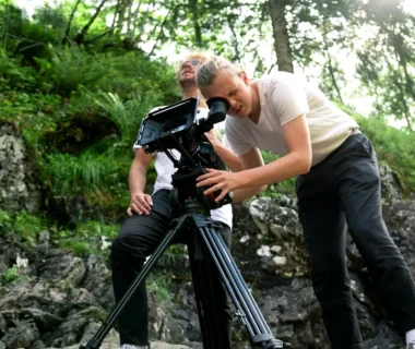 two men doing video recording while standing on rocks