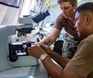 Two people working with a microscope in a lab.