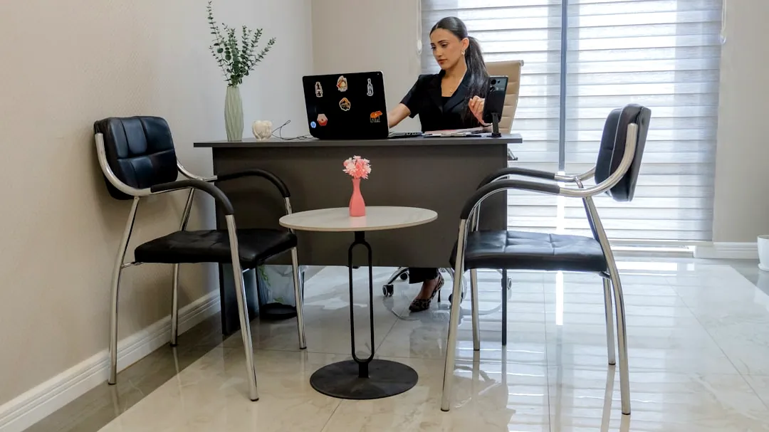Woman working at desk with laptop in office.