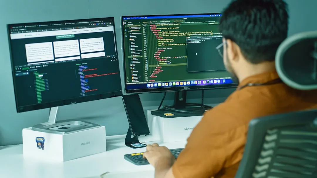 a man sitting in front of two computer monitors