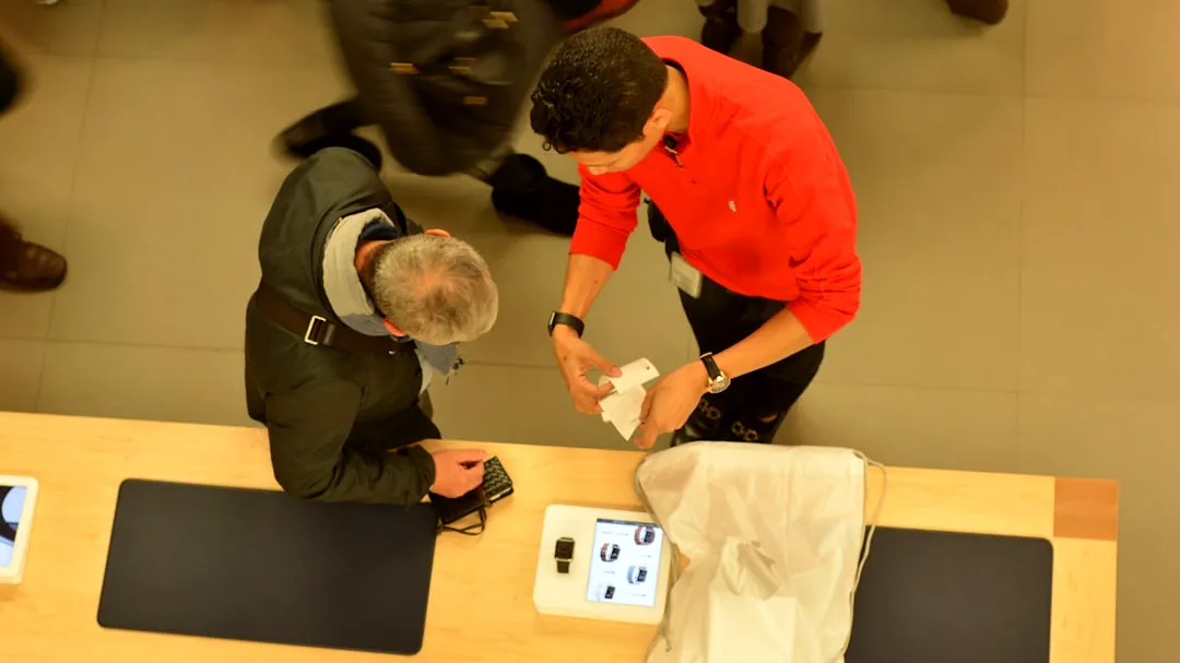 A store employee helps a customer at a counter.