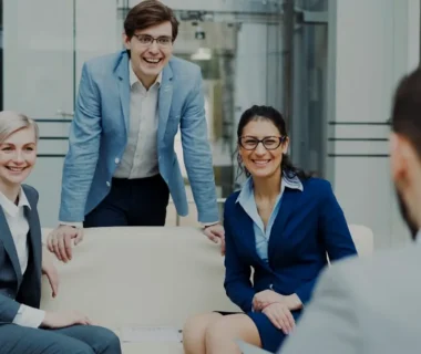 Four smiling business people in a modern office.