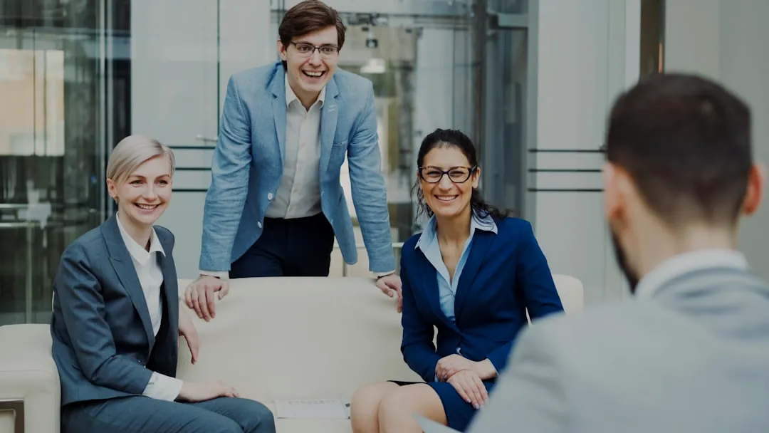 Four smiling business people in a modern office.