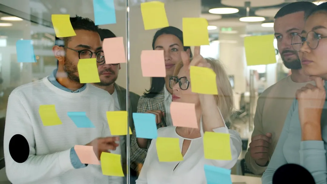 Team brainstorms using sticky notes on glass wall