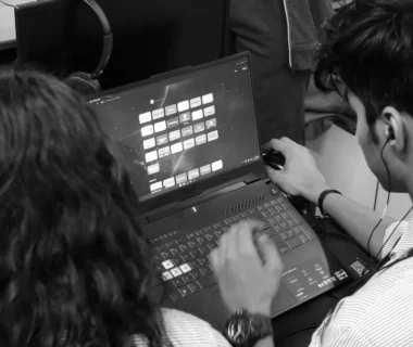a man and a woman sitting in front of a laptop computer