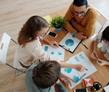 Diverse team collaborating around a table with charts.