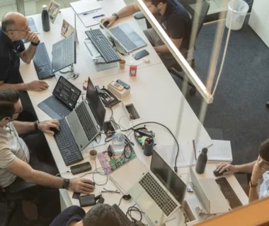 Four people working at desks in a modern office.