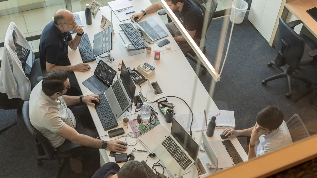 Four people working at desks in a modern office.