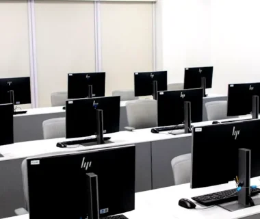 Spacious and minimalist computer lab with rows of black monitors and sleek furniture.