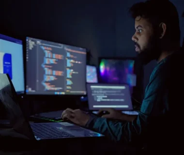A man sitting in front of three computer monitors