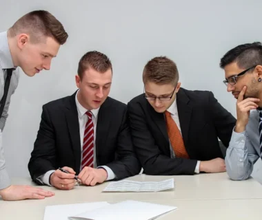four men looking to the paper on table